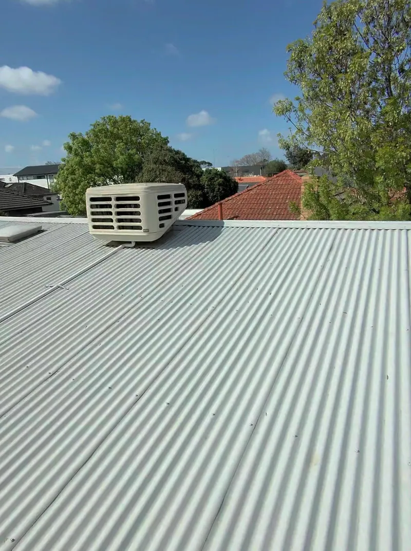 Evaporative cooler on a corrugated iron roof at the start of one of our services, tools laid out beside it