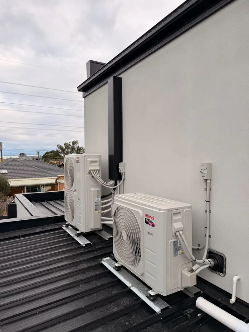 Reverse cycle outdoor units installed on a flat roof with a cover